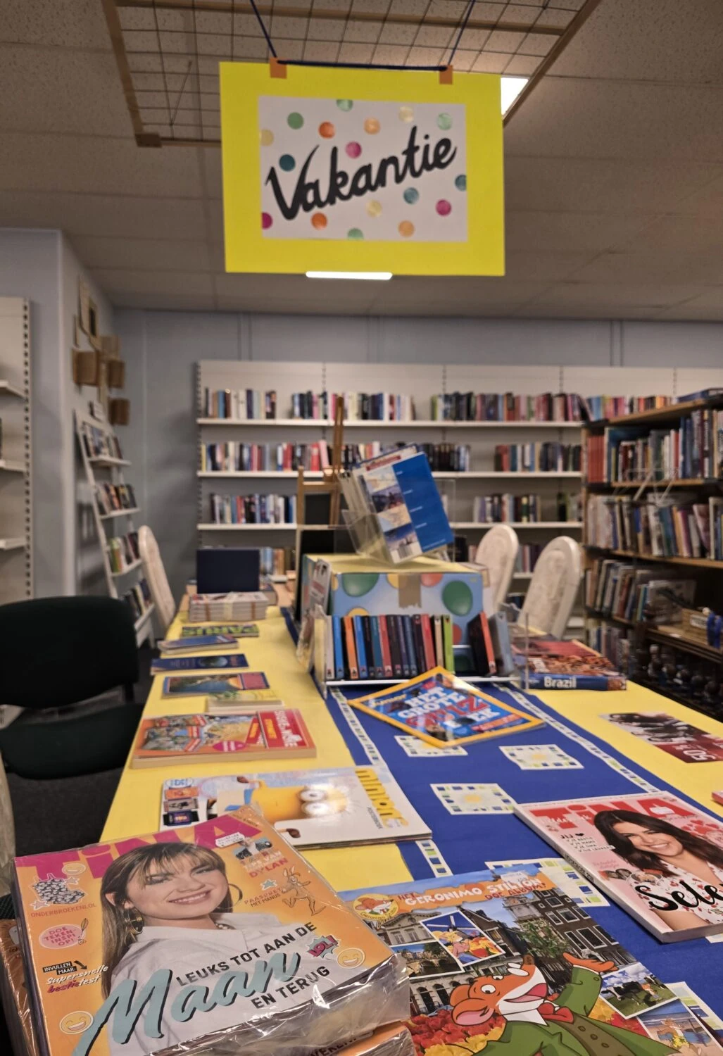 Bibliotheek met boeken en vakantie-informatie, promotie voor zomervakantie, gericht op educatie en ontspanning, in een humanitaire en educatieve context.