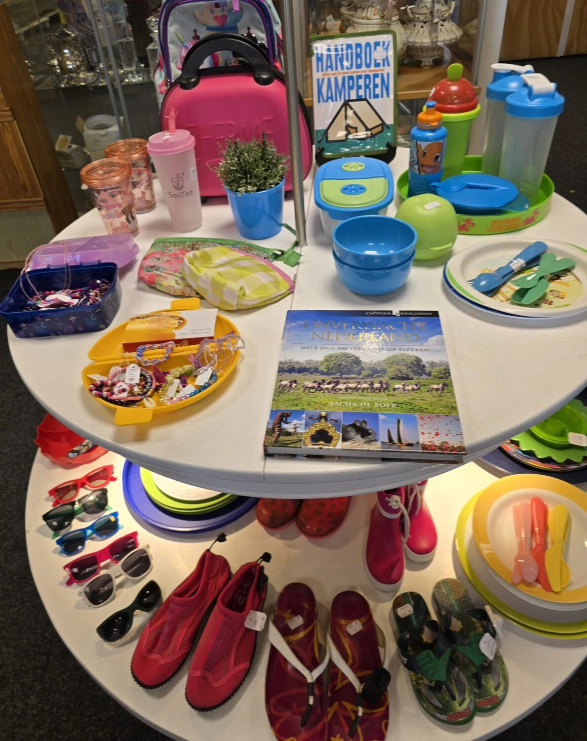 Diverse speelgoed en kinderartikelen op een tafel, inclusief schoenen, speelgoed, drinkbekers en boeken, symboliseert hulp en ondersteuning voor kinderen in ontwikkelingslanden.