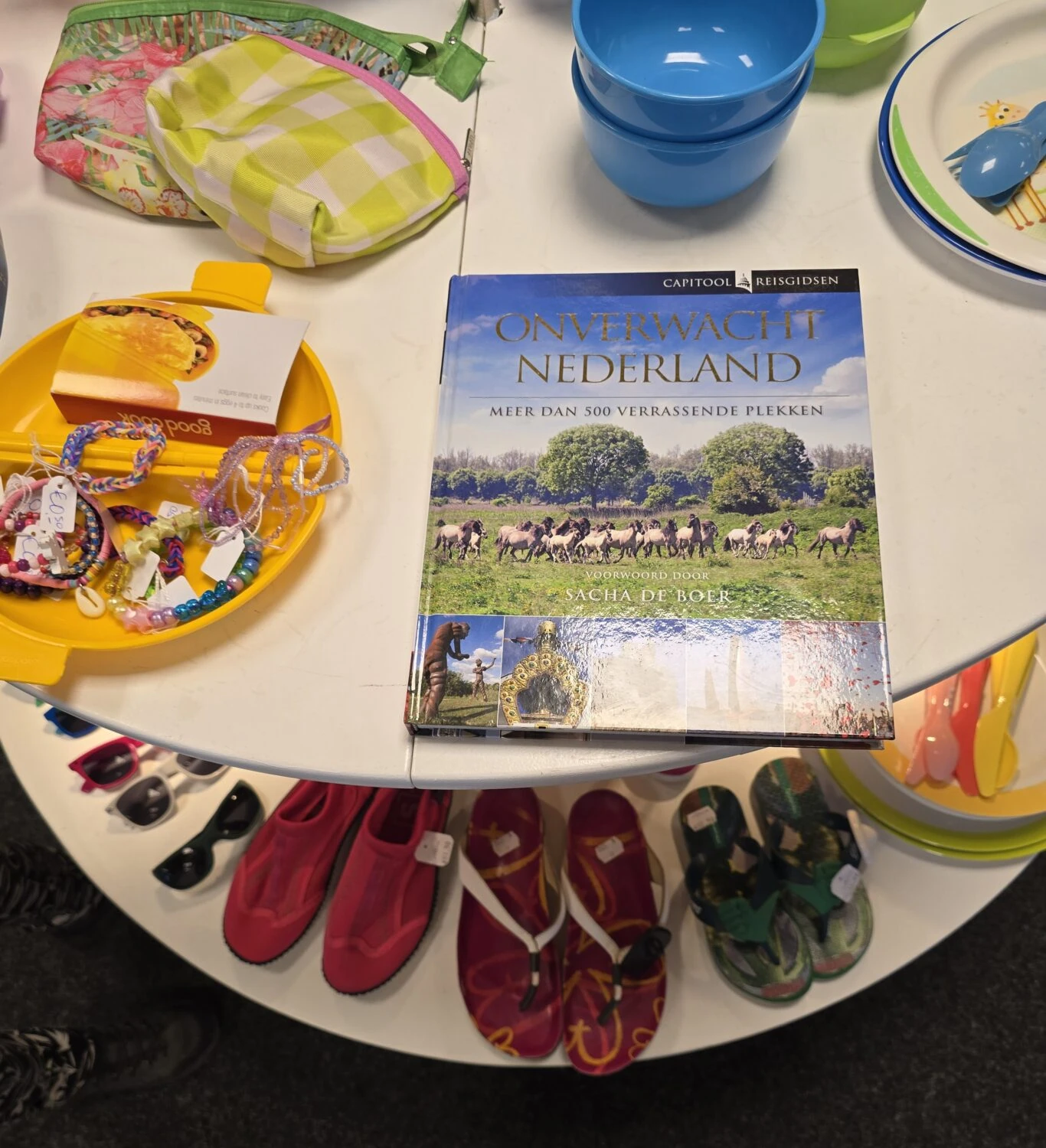 Diverse kinderspullen en een reisgids over Nederland op een tafel, symboliseert hulp en ontwikkeling voor kinderen in noodgebieden, passend bij Dorcas' missie voor humanitaire hulp en armoedebestrijd.