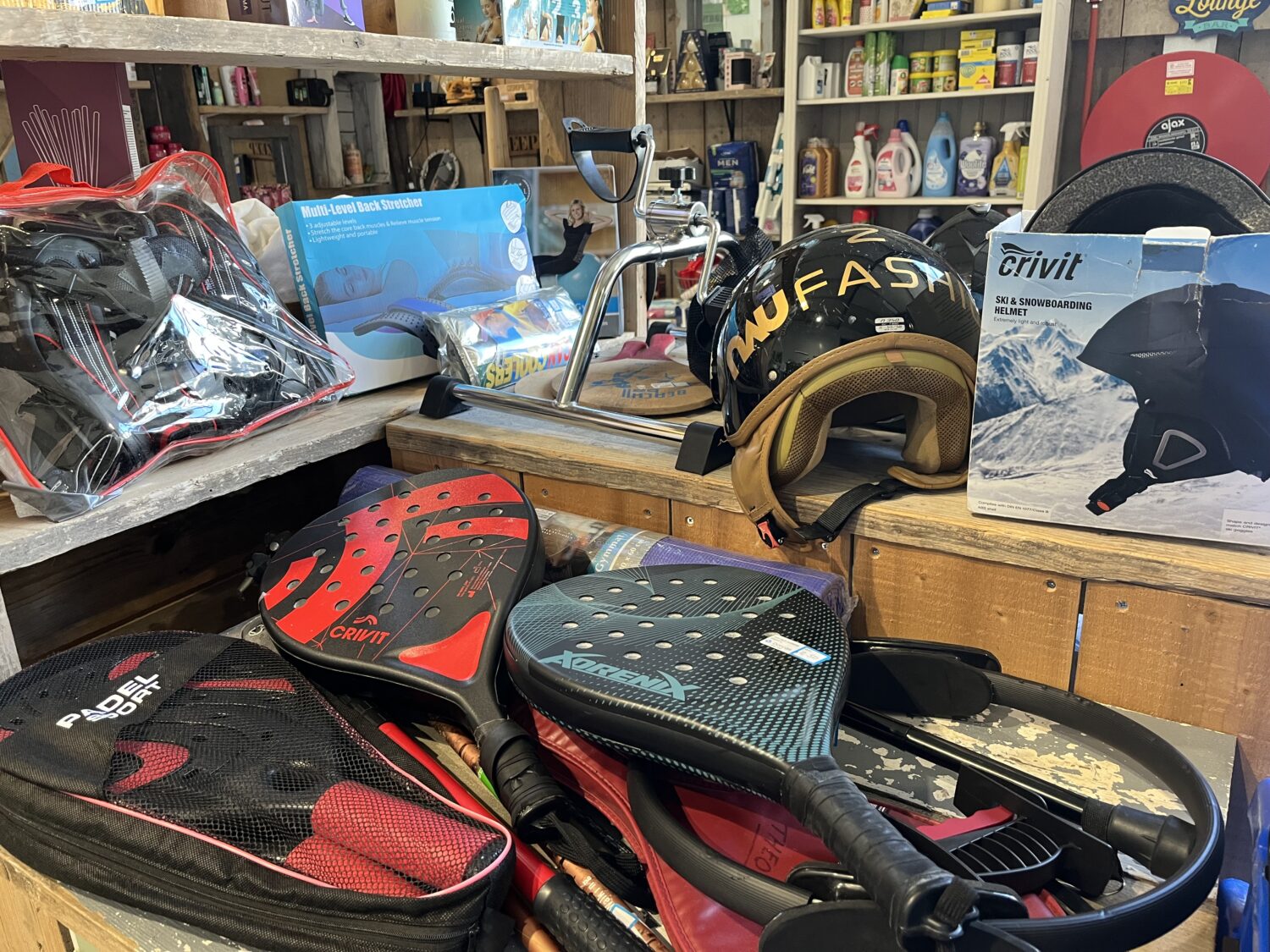 Diverse sport- en veiligheidsuitrusting, waaronder helmen, skates en beschermingskleding, in een winkel voor noodhulp en ontwikkelingssamenwerking, gericht op armoedebestrijding en humanitaire hulp.