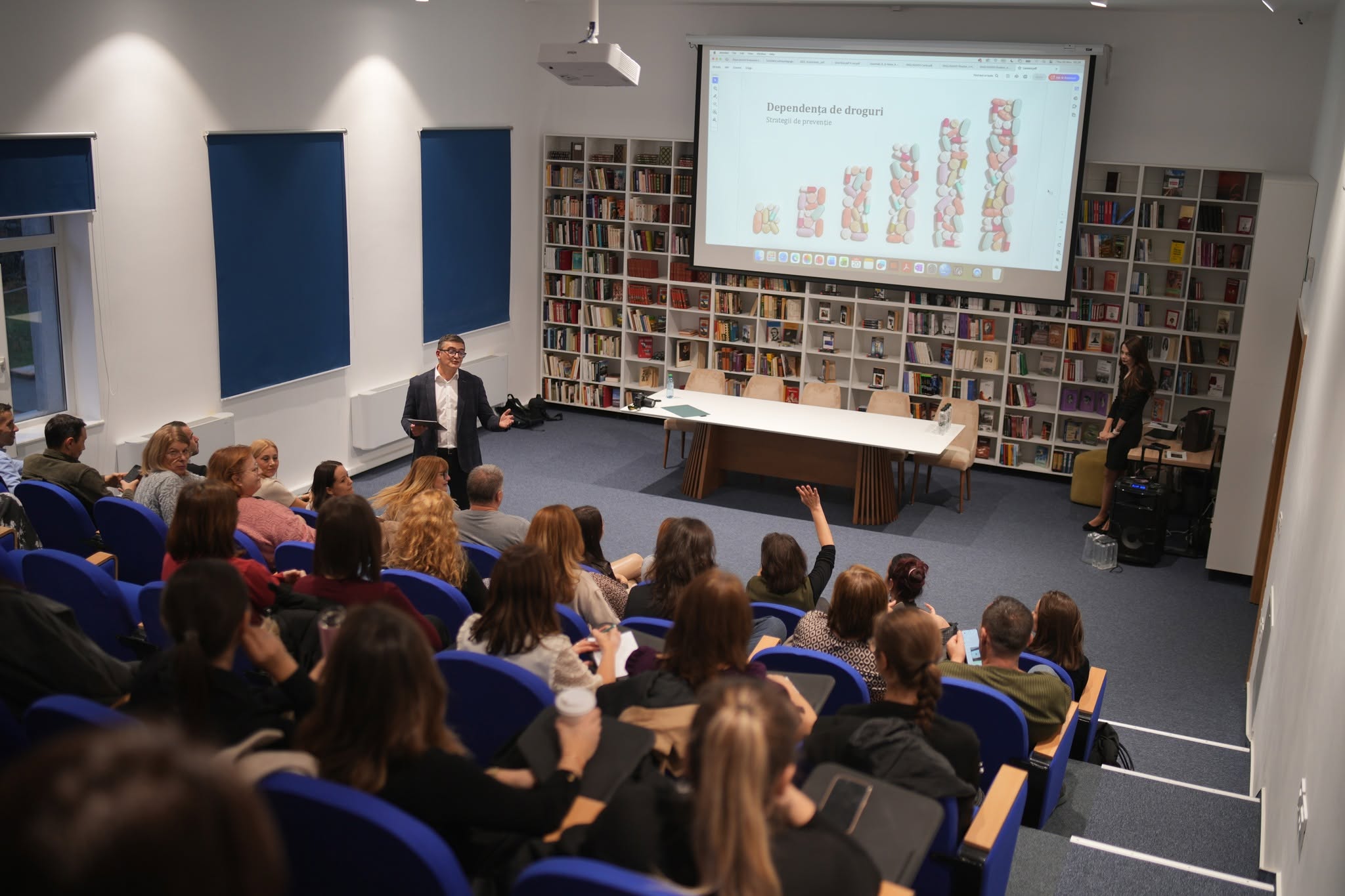Een presentatie over humanitaire hulp en armoedebestrijding voor een zaal vol geïnteresseerden, passend bij de missie van Dorcas voor noodhulp en ontwikkelingssamenwerking.