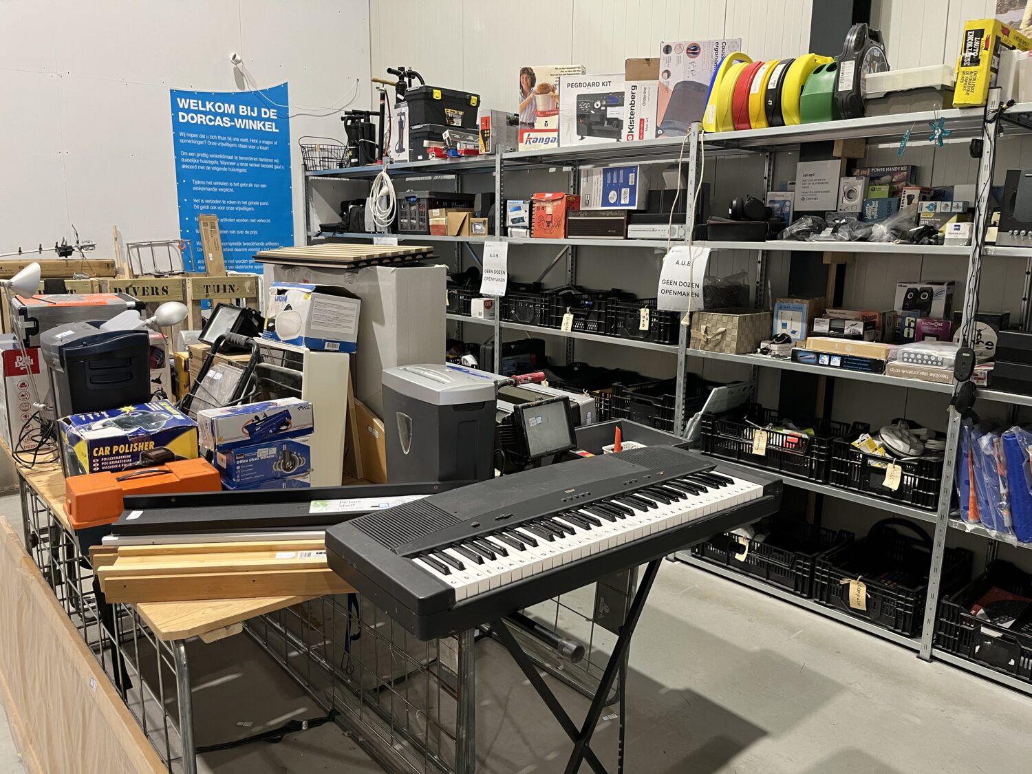 Binnen in een winkel met diverse elektronische apparaten, accessoires en een keyboard, gericht op humanitaire hulp en noodhulpvoorzieningen voor ontwikkelingssamenwerking.
