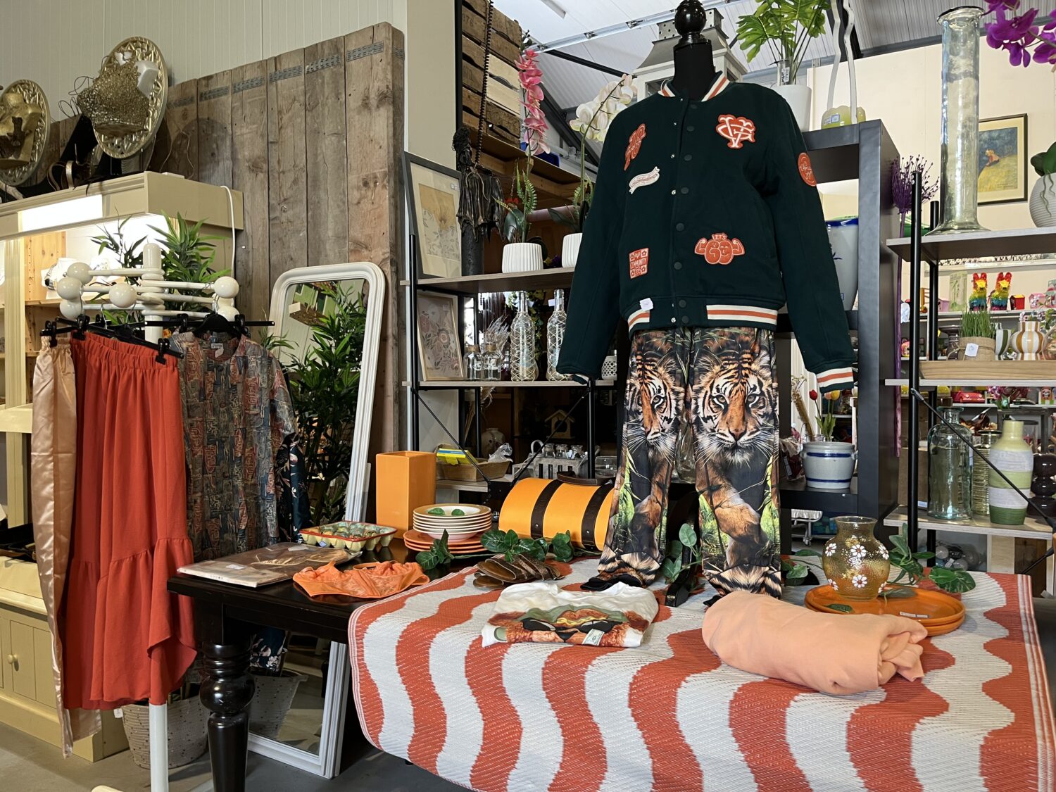 Een tweedehandswinkel met diverse kleding, accessoires en decoratie, gericht op humanitaire hulp en armoedebestrijding, met kleurrijke en duurzame items voor een betere wereld.