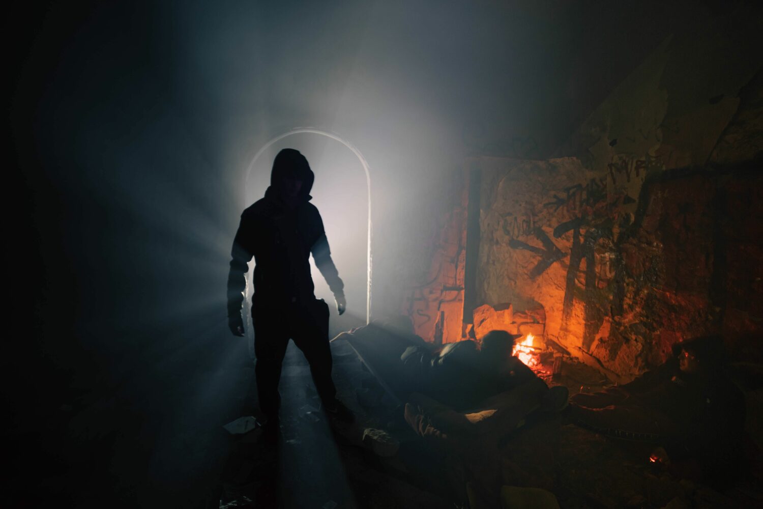 Hulpverleners bieden humanitaire hulp in een donkere, gevaarlijke omgeving met een heldere lichtstraal en een muur met graffiti, benadrukt de inzet voor noodhulp en armoedebestrijding.