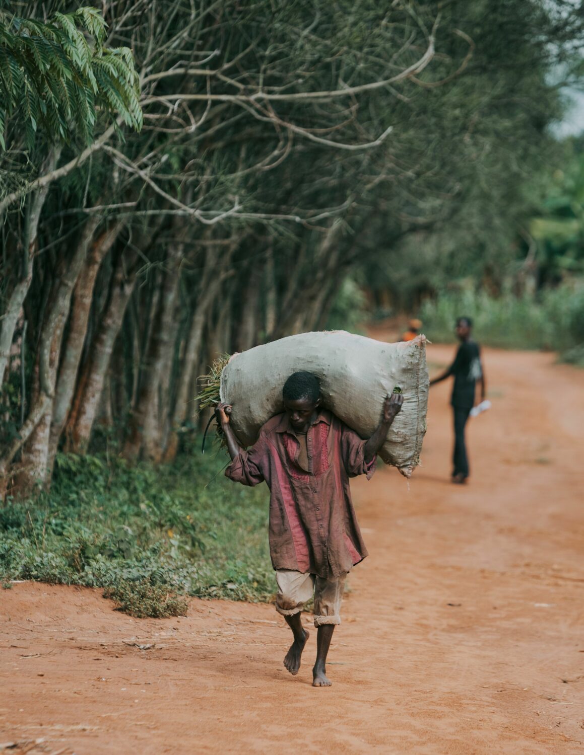 Een kind draagt een grote zak op de schouder tijdens humanitaire hulp in Oost-Afrika, een gebied waar Dorcas zich inzet voor armoedebestrijding en noodhulp.