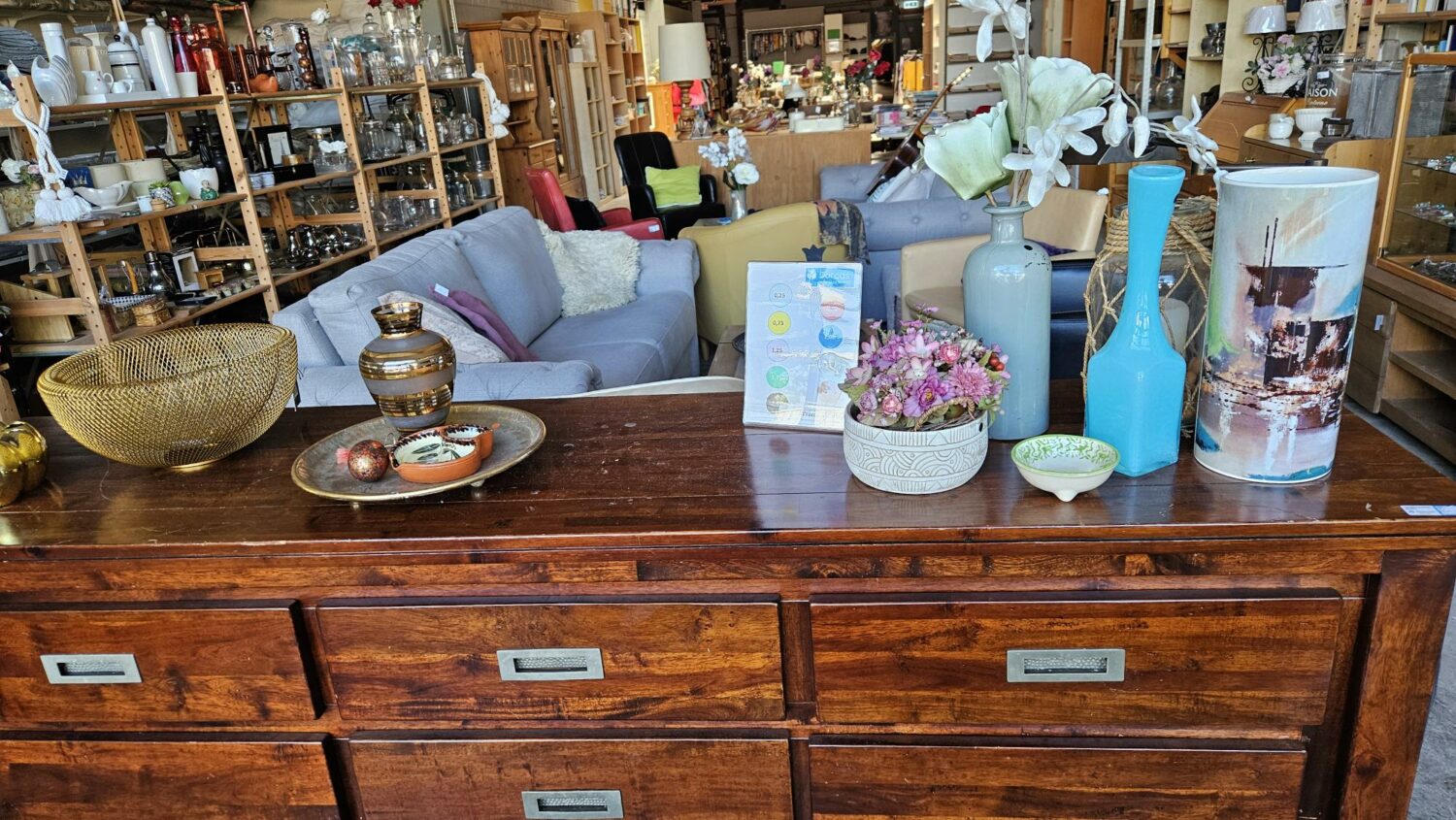 Interieur van een winkel met houten meubelen, vazen en decoratieve items, gericht op humanitaire hulp en armoedebestrijding, passend bij de missie van Dorcas.