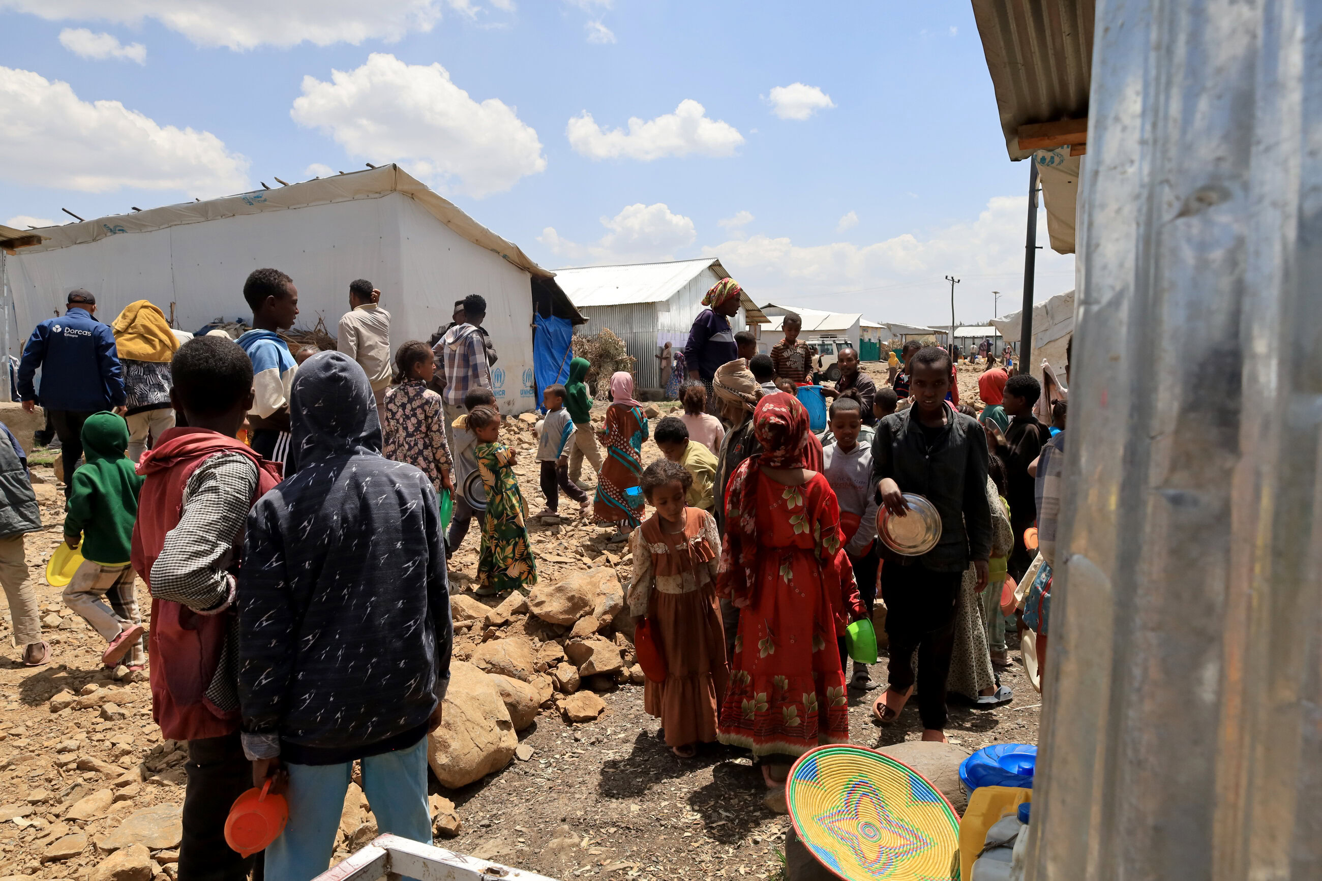 Hulpverleners en vluchtelingen in Ethiopië wachten op noodhulp in een vluchtelingenkamp, met tenten en mensen die zich voorbereiden op verdere hulpverlening.