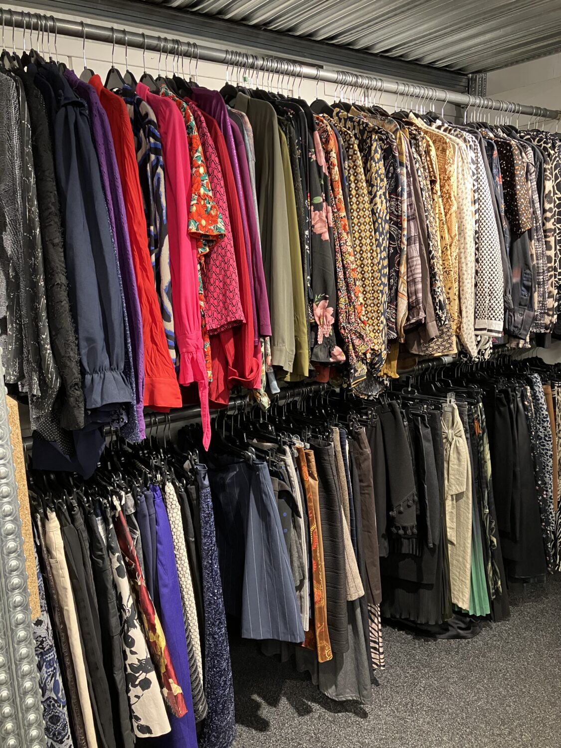 Diverse kledingstukken hangen aan een winkelrek, klaar voor donatie of verkoop, symboliseert hulp en ondersteuning voor mensen in nood, passend bij de missie van Dorcas.
