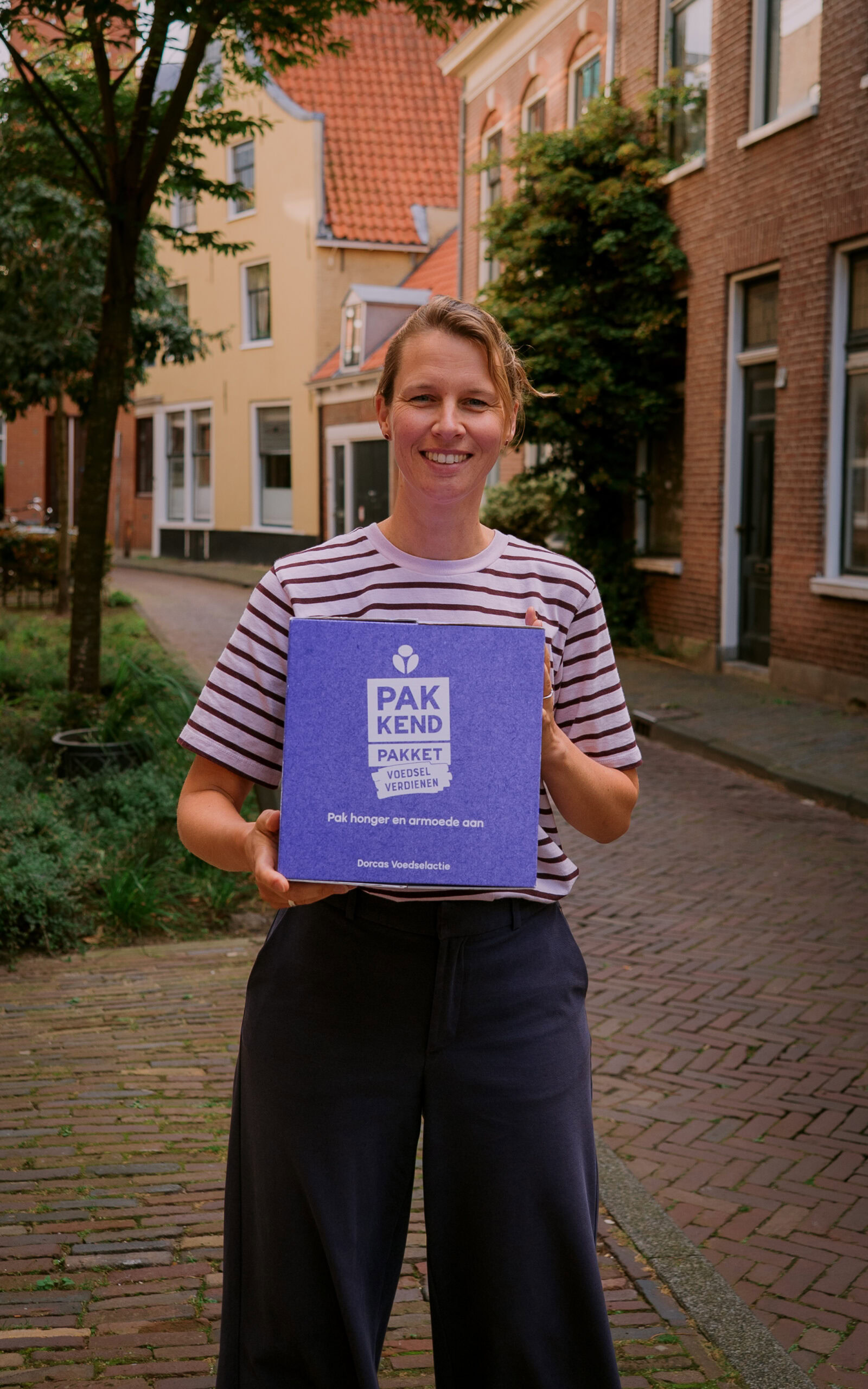 Vrouw houdt een PAKKET voor humanitaire hulp vast, symbool voor noodhulp en armoedebestrijding in Oost-Europa, passend bij Dorcas' missie.