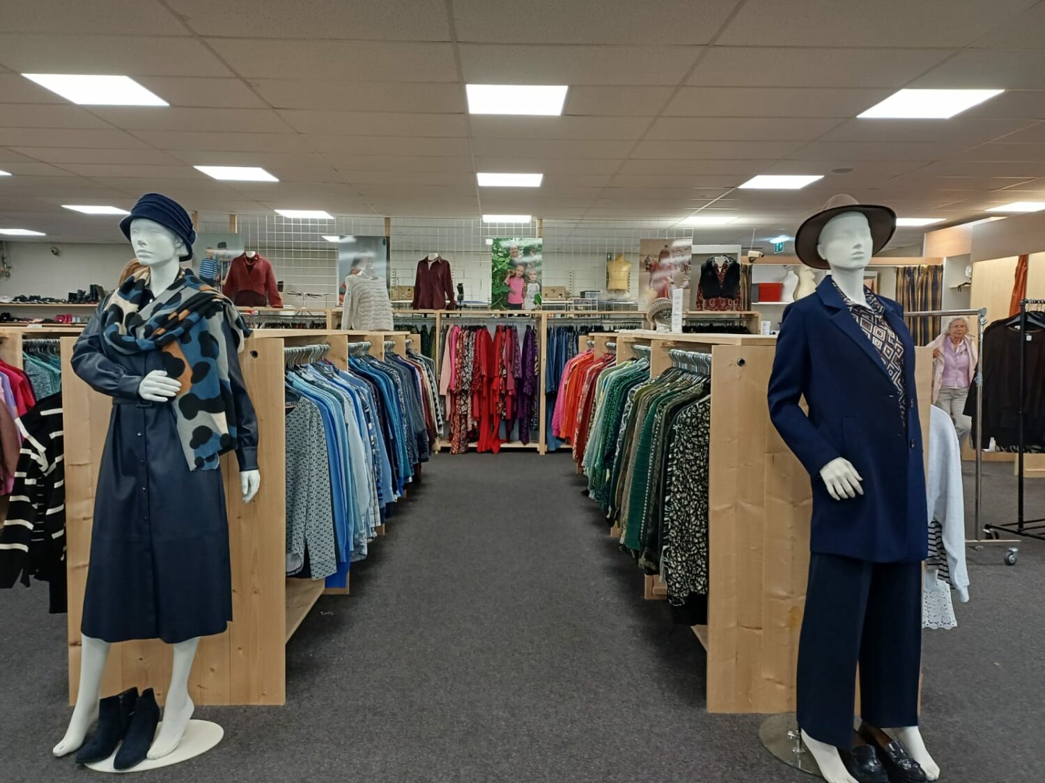 Mannequins in een kledingwinkel met diverse kledingrekken en accessoires, symboliseert humanitaire hulp en armoedebestrijding door Dorcas.