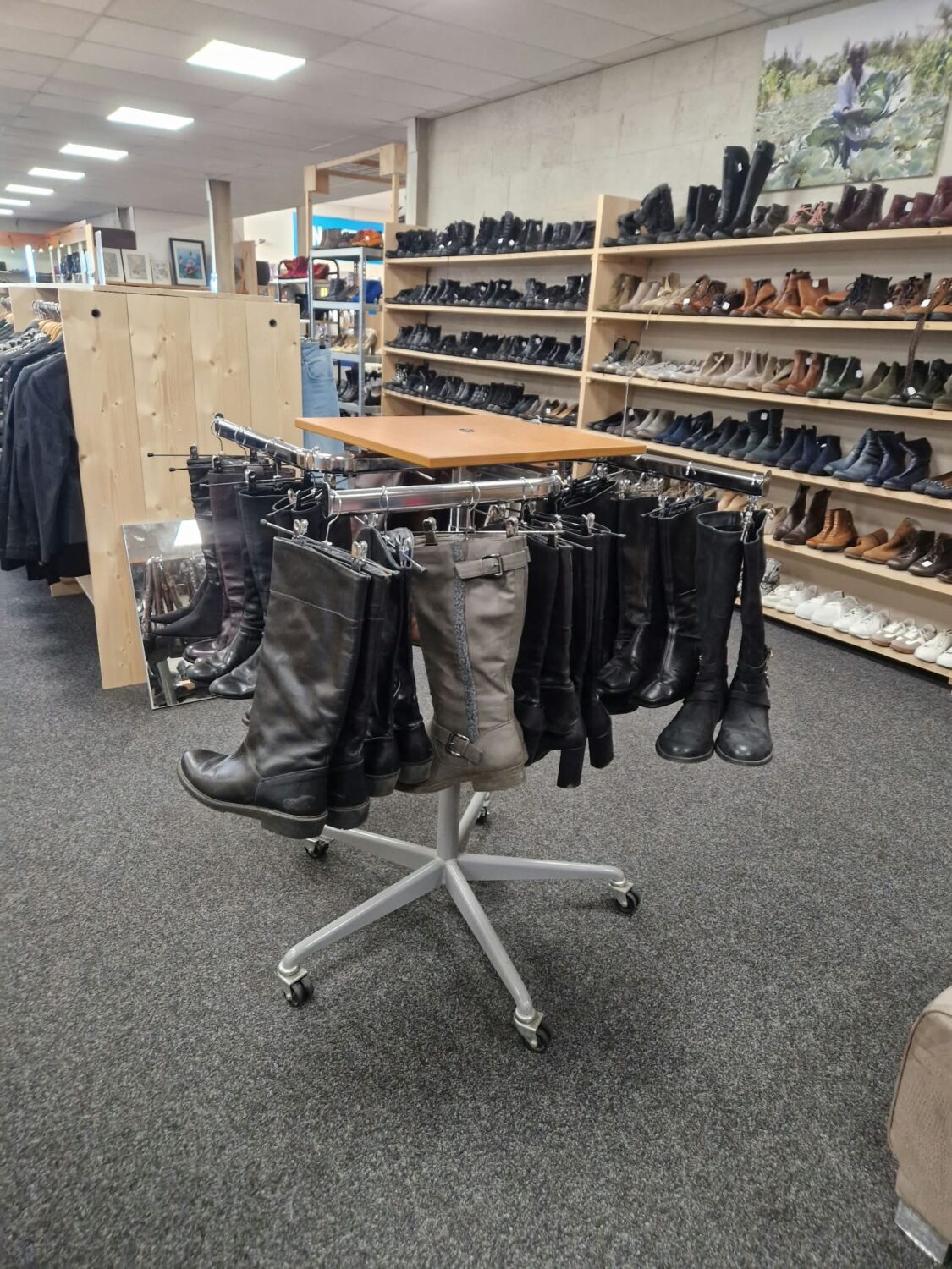 Diverse schoenen en laarzen in een winkel, gericht op noodhulp en armoedebestrijding, met een overzicht van schoenenrekken en een tafel in een winkelomgeving.