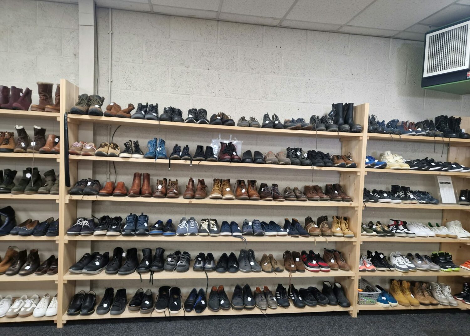 Schoenenwinkel met meerdere planken vol diverse schoenen, inclusief boots, sneakers en loafers, voor humanitaire hulp en armoedebestrijding in Oost-Europa, Oost-Afrika en het Midden-Oosten.