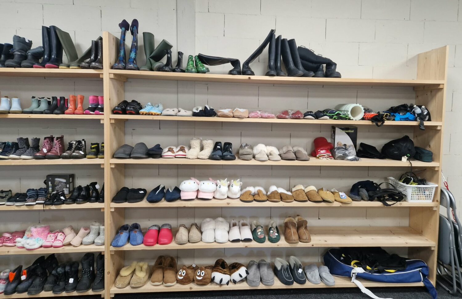 Schoenen en slippers op houten rekken, onderdeel van een donatie- of distributiecentrum voor humanitaire hulp door Dorcas, gericht op armoedebestrijding en noodhulp.