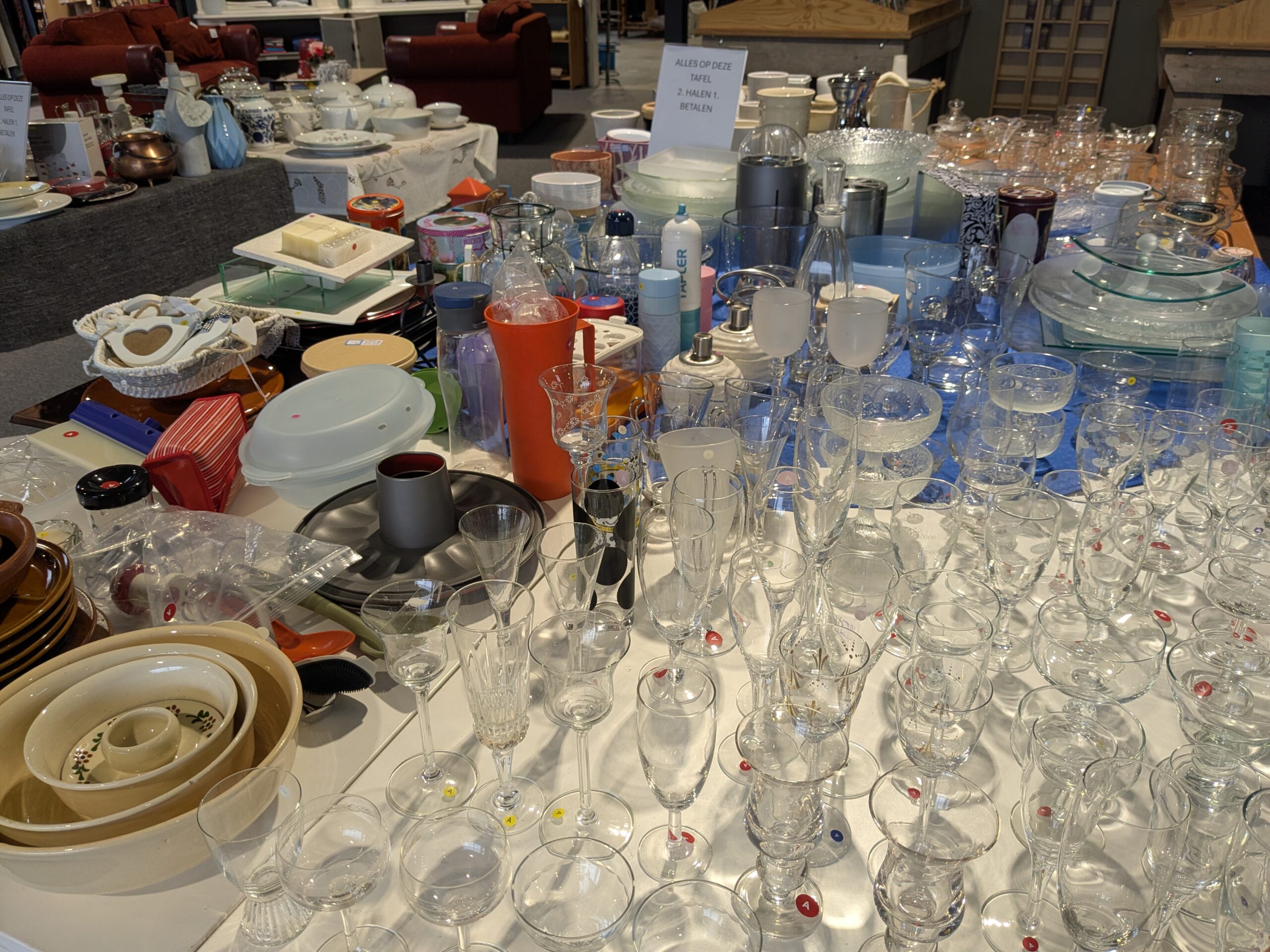 Diverse glazen en serviesgoed op een marktstand, geschikt voor humanitaire hulp en armoedebestrijding, met een focus op noodhulp en ontwikkelingssamenwerking.