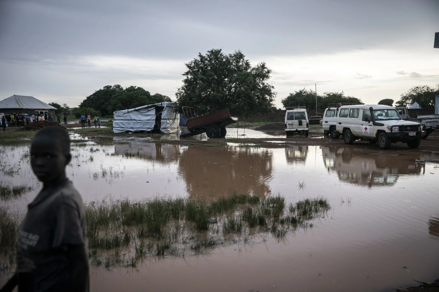 Noodhulpactie met voertuigen en mensen in overstromingsgebied, benadrukt humanitaire hulp en armoedebestrijding in Oost-Afrika, passend bij Dorcas' missie.