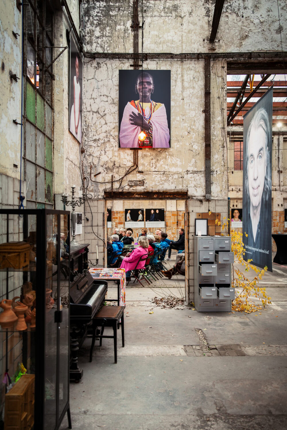 Een groep mensen in een industrieel gebouw, omringd door kunstwerken en foto's die vrede en humanitaire hulp symboliseren, passend bij de missie van Dorcas.