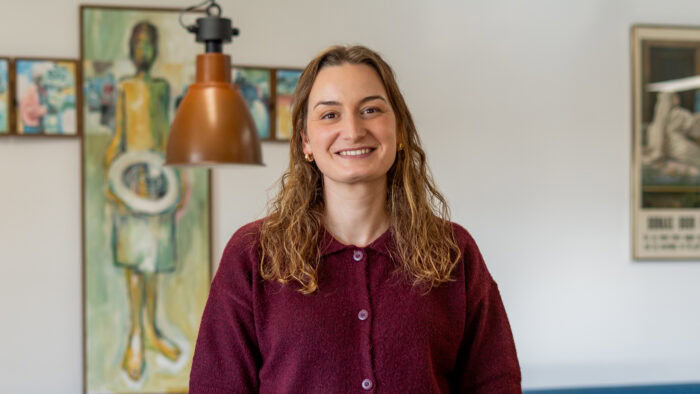 Vrouw met warme trui in kunstgalerie, symboliseert hoop en ondersteuning in humanitaire hulp, passend bij Dorcas' missie voor noodhulp en armoedebestrijding.