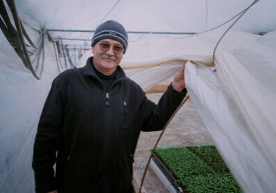 Attila header Zachtlopende man in kas met jonge plantjes onder een kasdoek.