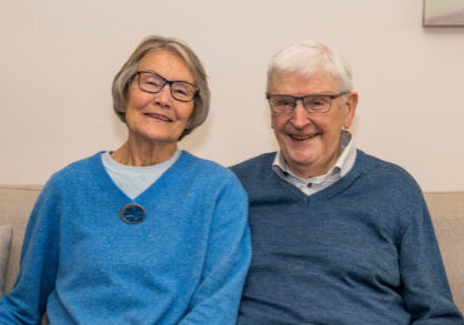 Een gelukkige oudere koppel zit samen op een bank, lachend en genietend van elkaars gezelschap, symboliseert verbondenheid en geluk in de latere jaren.