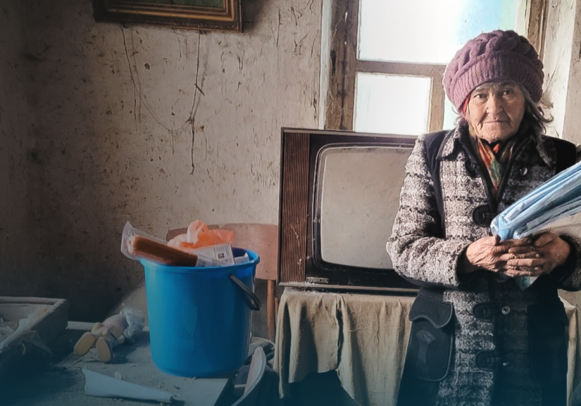 Een vrouw in een armzalige kamer ontvangt hulp en houdt documenten vast, symboliseert de noodhulp voor Oekraïne en de inzet van Dorcas voor humanitaire ondersteuning.