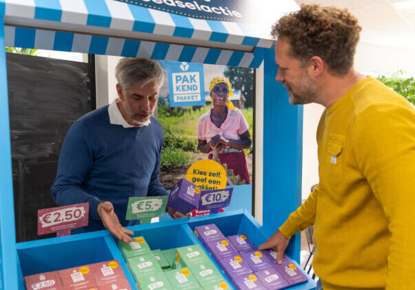 Dorcas Voedselactie kraam header Dames en heren kopen gezonde producten bij een steunt Kiosk voor ontwikkelingshulp.