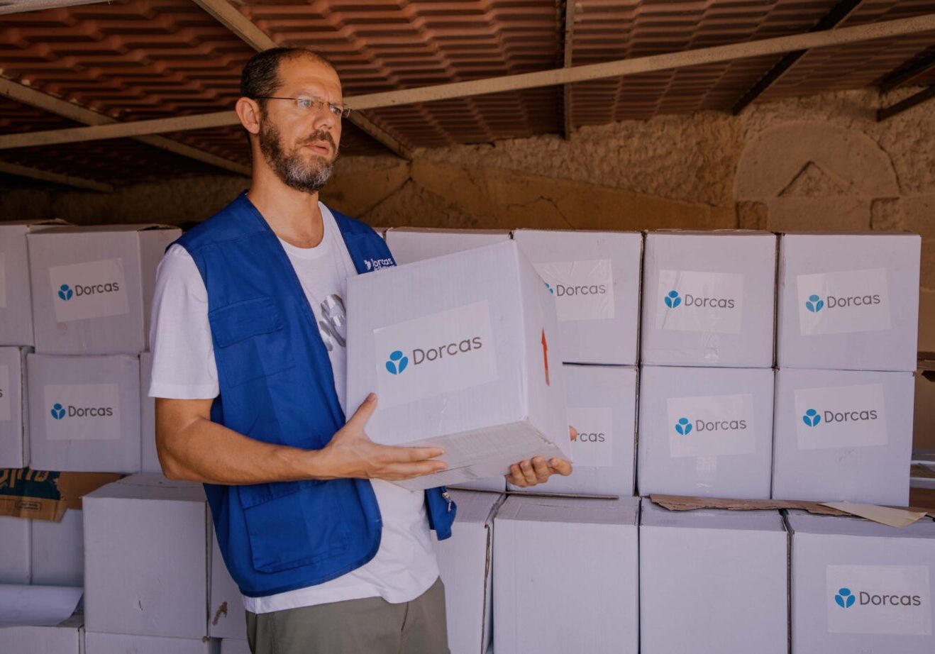 Het CNC, christelijk noodhulpcluster komt in actie met Dorcas als christelijk goed doel actief in landen met grote nood. Op de foto een medewerker die voedsel uitdeelt met een grote witte doos met daarin de benodigheden om te overleven.